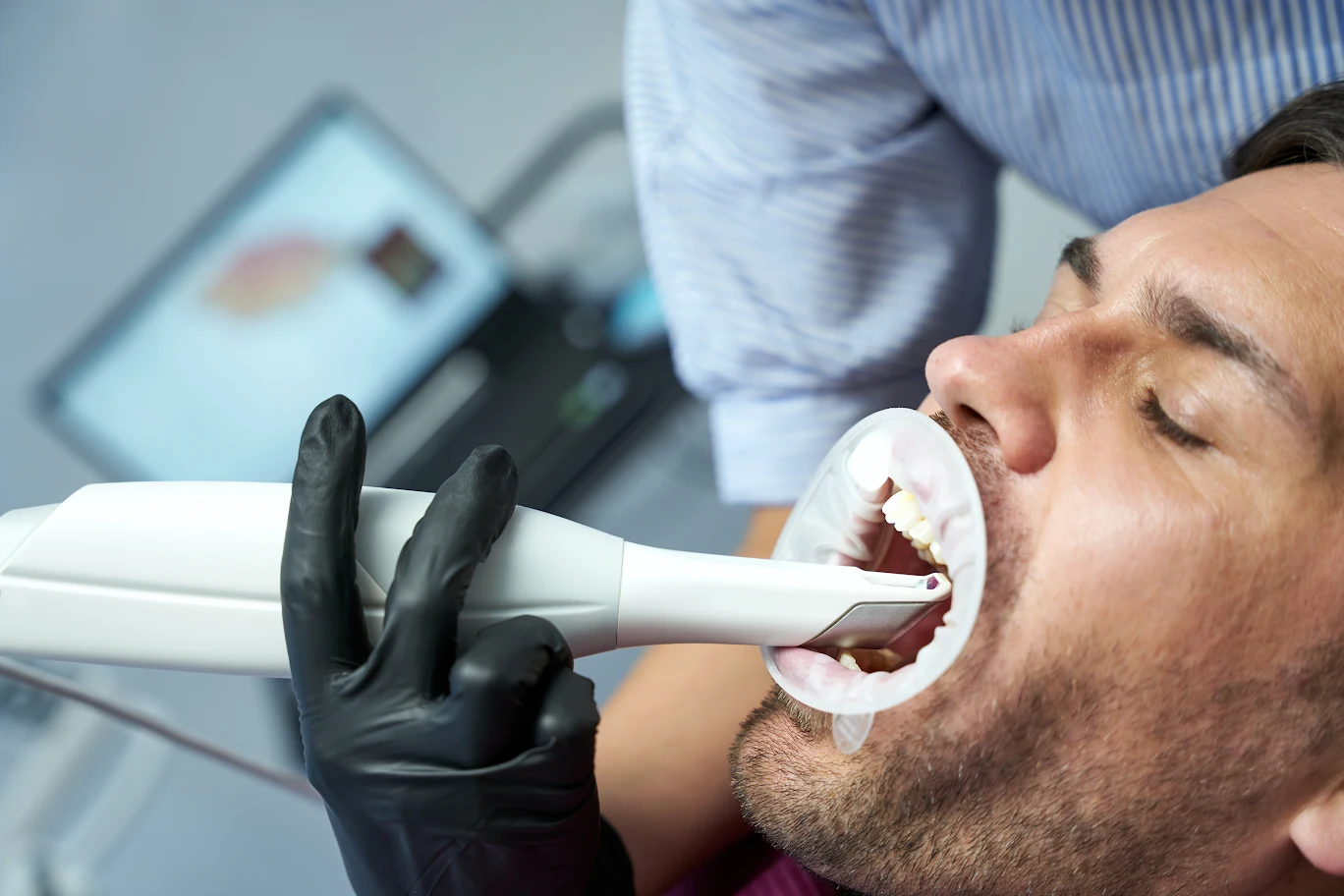 Dentist using a dental scanner on a patient's teeth.