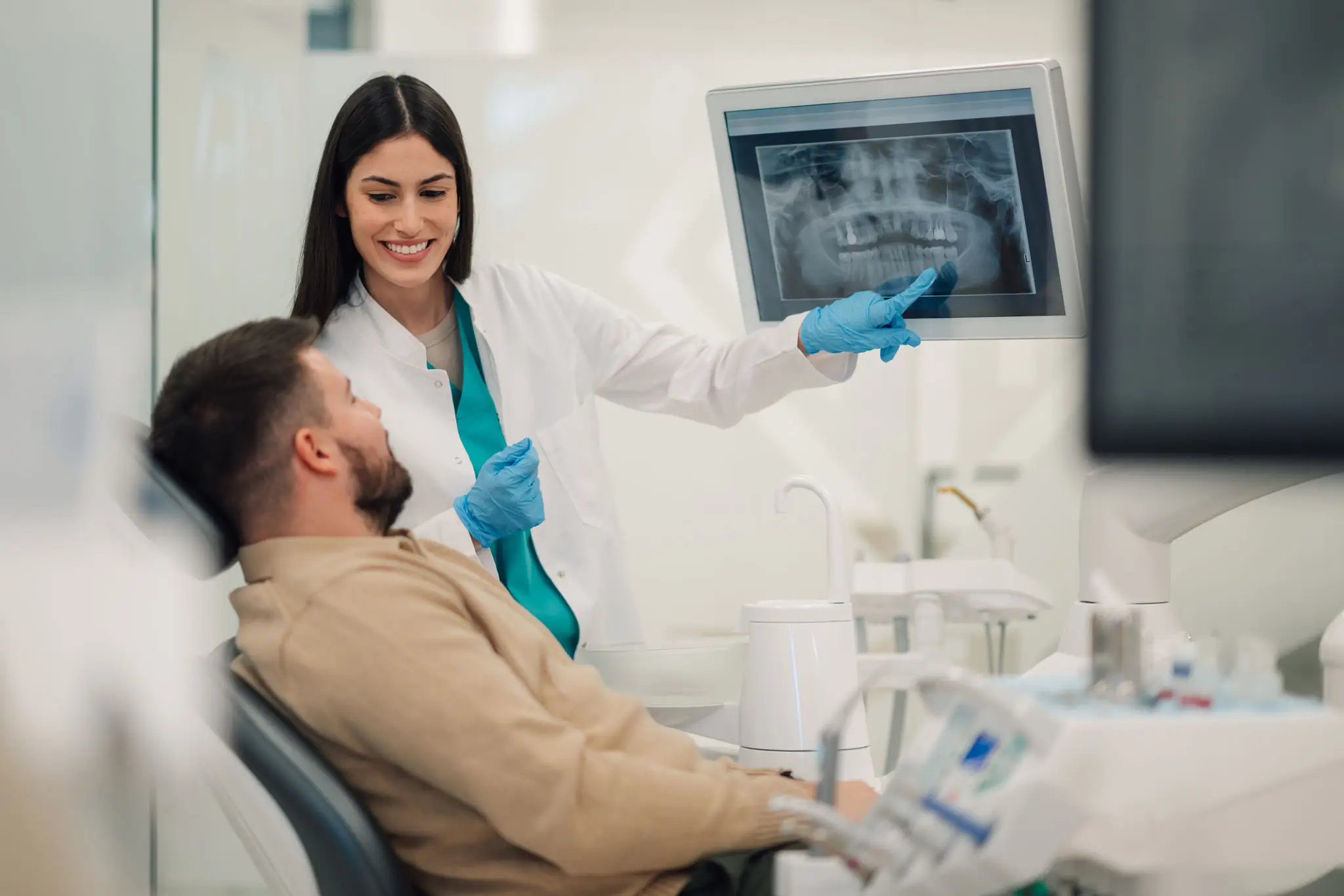 Dentist showing dental X-ray to a patient in clinic.